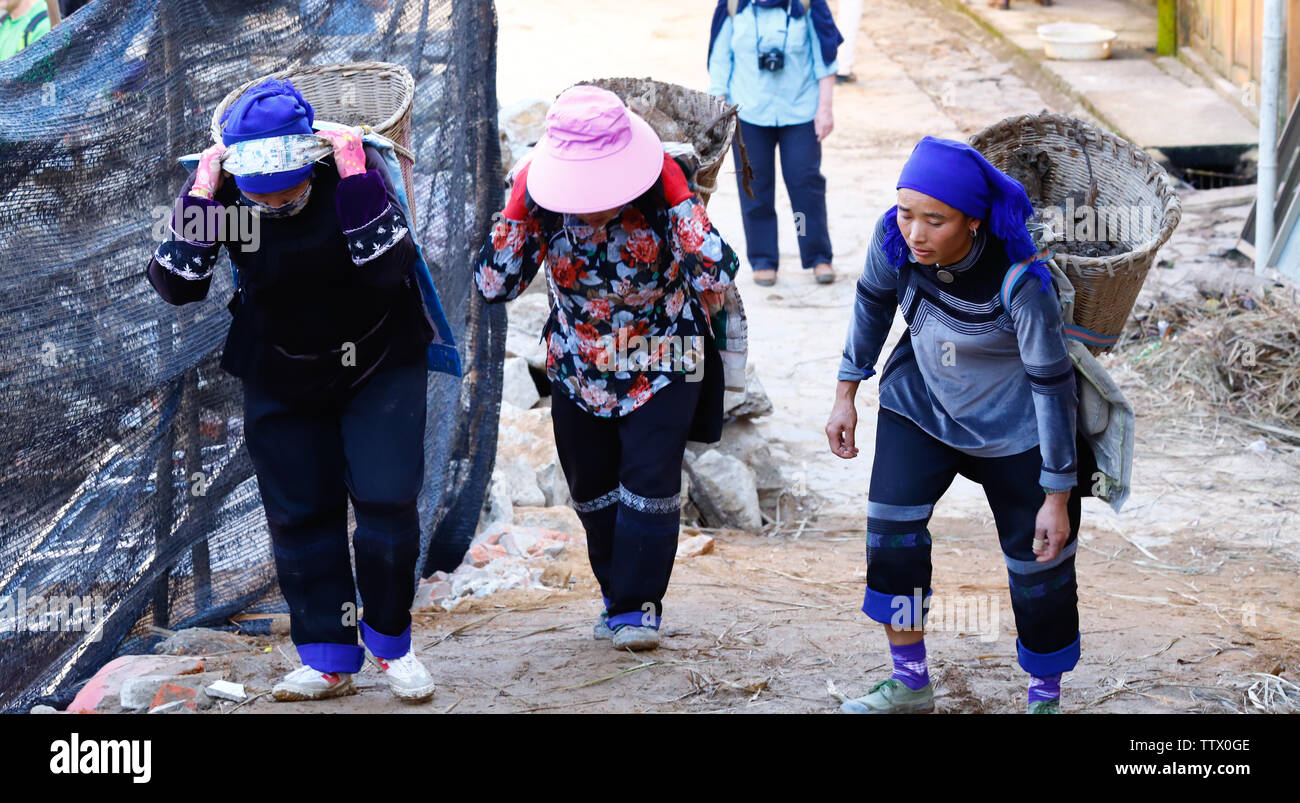 Women at work in a village near the rice fields of Yunnan, China. The famous terraced rice fields of Yuanyang in Yunnan province in China. Yunnan, Chi Stock Photo