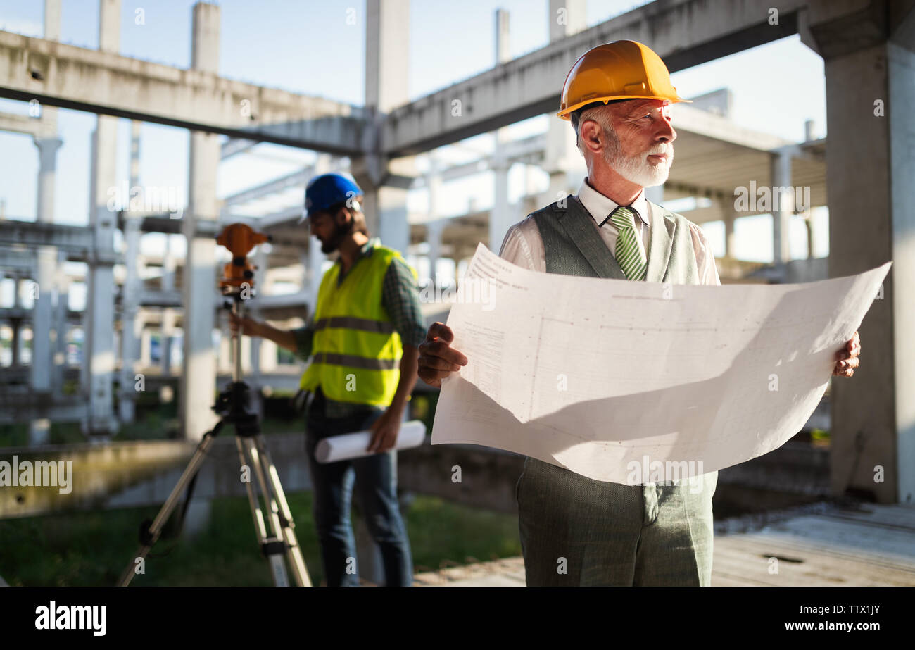 Engineer and construction site manager dealing with blueprints and ...