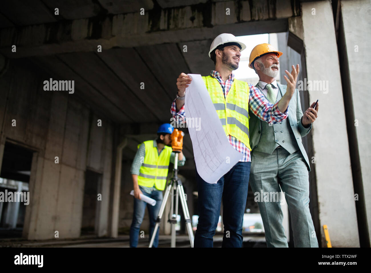 Engineer, foreman and worker discussing in building construction site Stock Photo