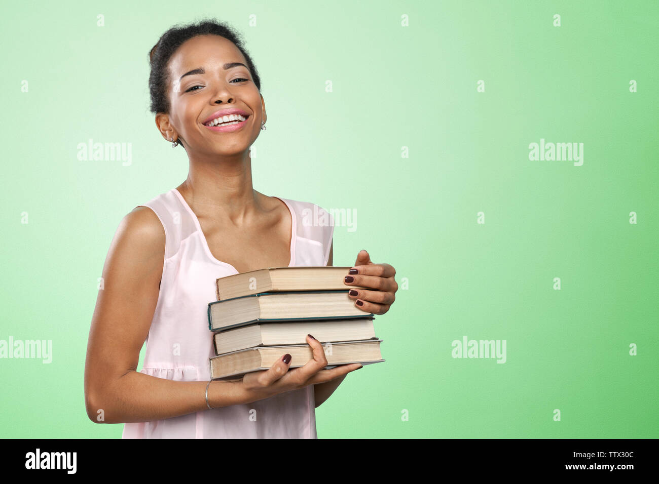 African american woman holding a pile of books Stock Photo - Alamy