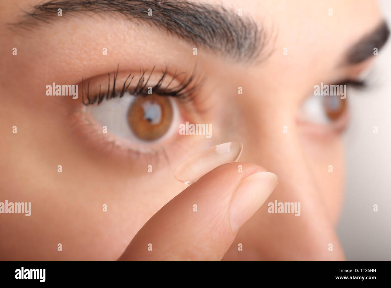 Young woman putting contact lens in her eye, close up view. Medicine and vision concept Stock Photo