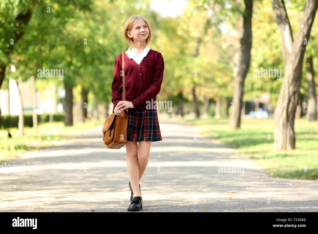 Schoolgirl walking along alley in green park Stock Photo - Alamy