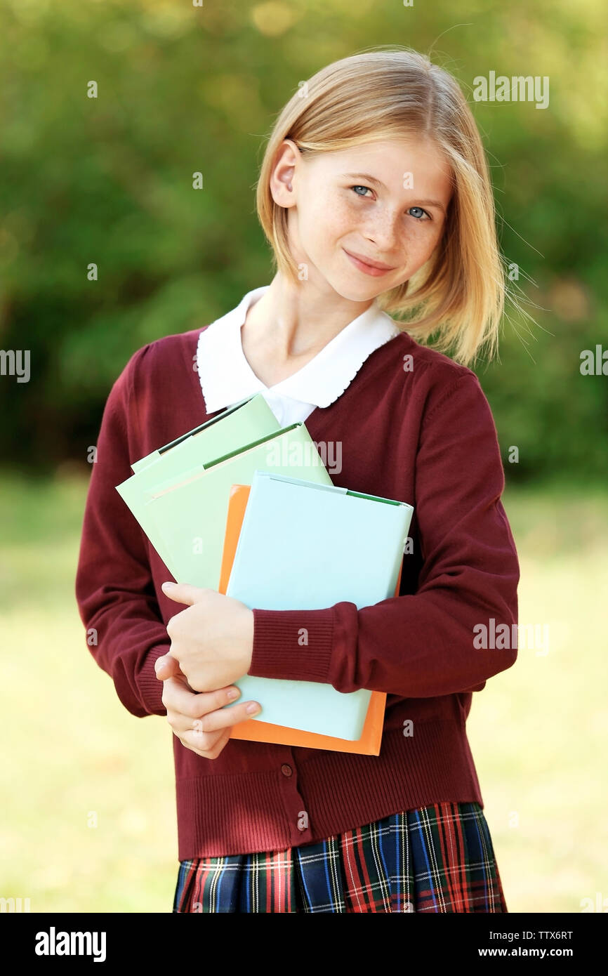 Schoolgirl with books outdoors on blurred background Stock Photo - Alamy