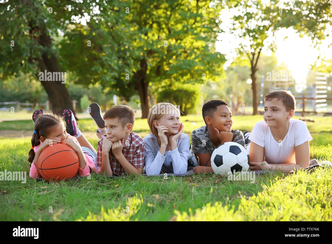 Cute kids with sport balls on green grass Stock Photo - Alamy