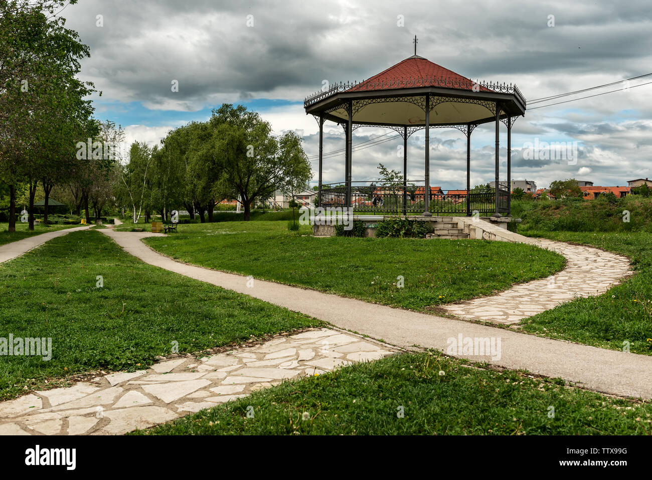 Gazebo or a pavilion on green lawn at the end of a stone pathway Stock Photo