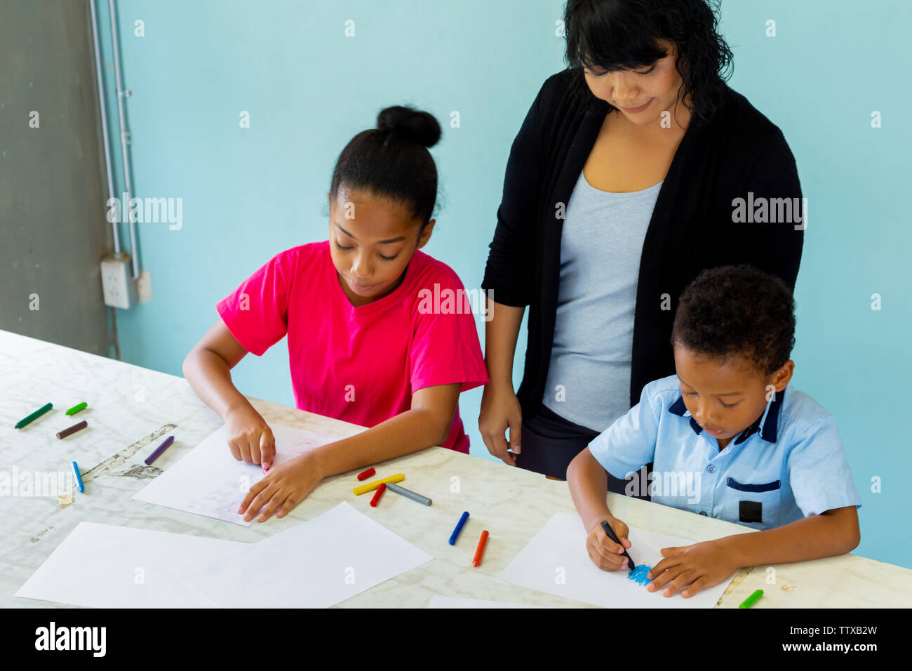 Young teacher giving african american kids an art lesson and teaching