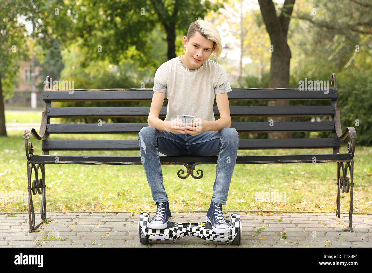 Cute teenager boy sitting on bench in park Stock Photo - Alamy