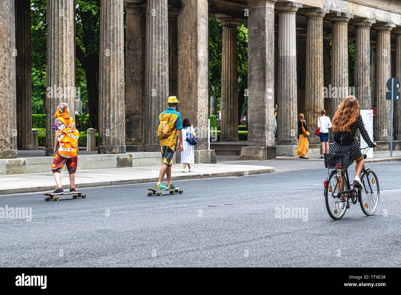 Young tourists in colourful clothing enjoying Summer, Museum Island, Mitte,Berlin. Two skate boarders & female cyclist Stock Photo