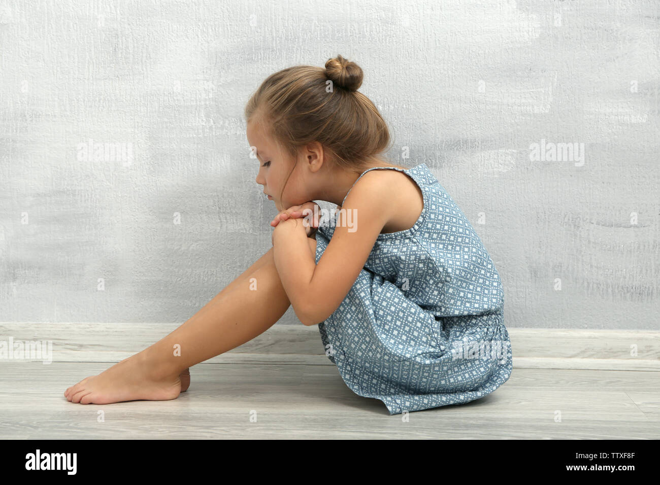 Sad little girl sitting on floor in empty room Stock Photo - Alamy
