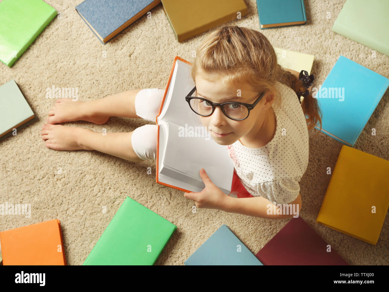 Cute girl with books sitting on floor Stock Photo - Alamy
