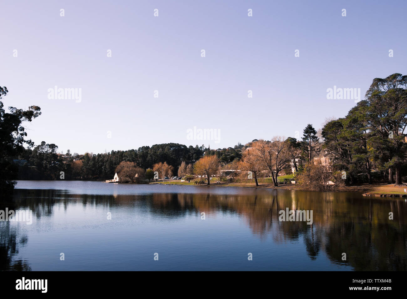 Image of a lake with trees and tree reflections, with a vast blue and purple sky Stock Photo