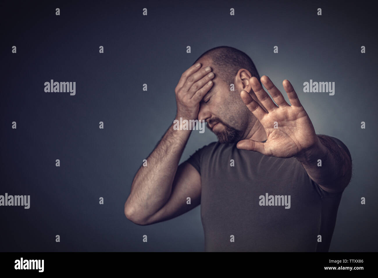 Portrait of a stressed man with his eyes closed and his hand on his forehead. gesture of those who keep people away. Stock Photo