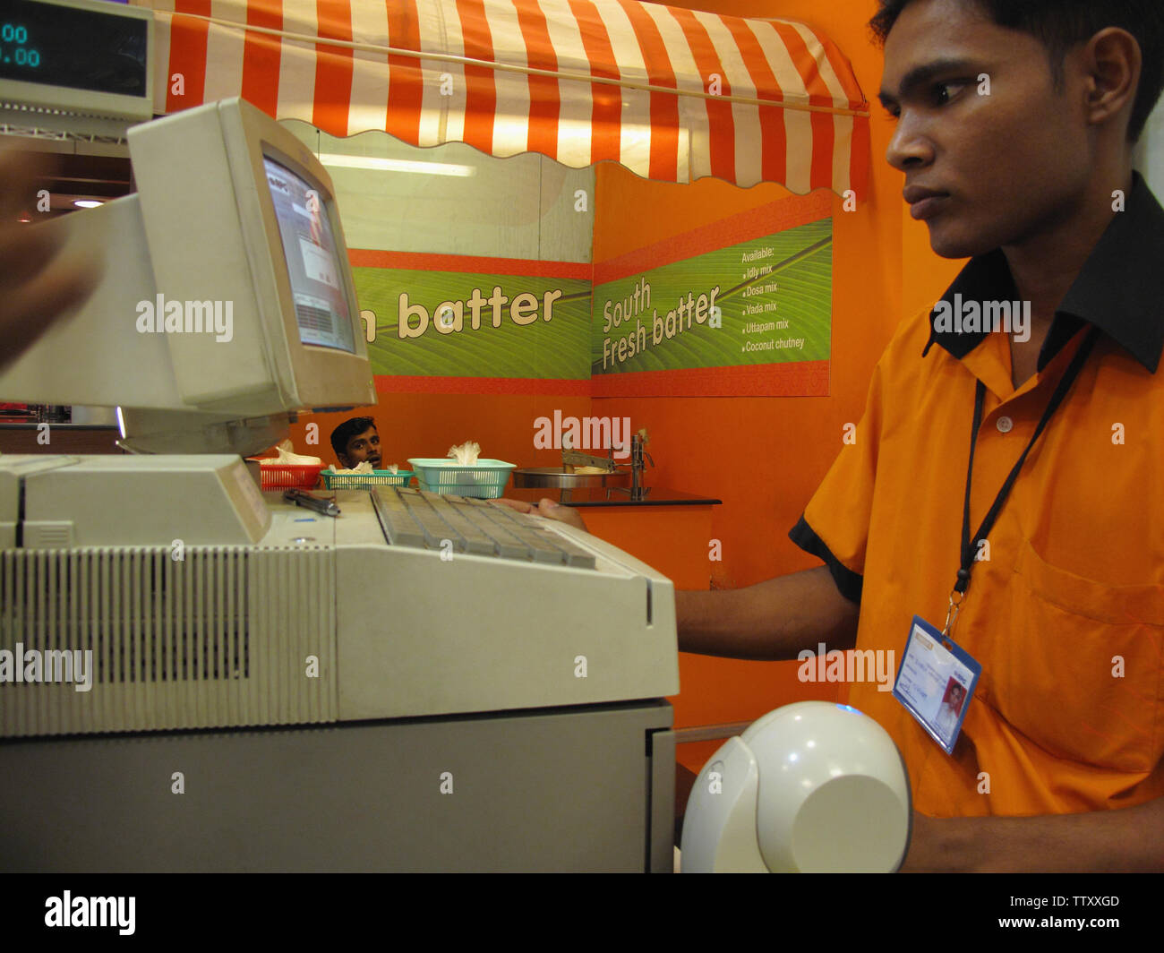 Sales clerk using a computer at a checkout counter, India Stock Photo
