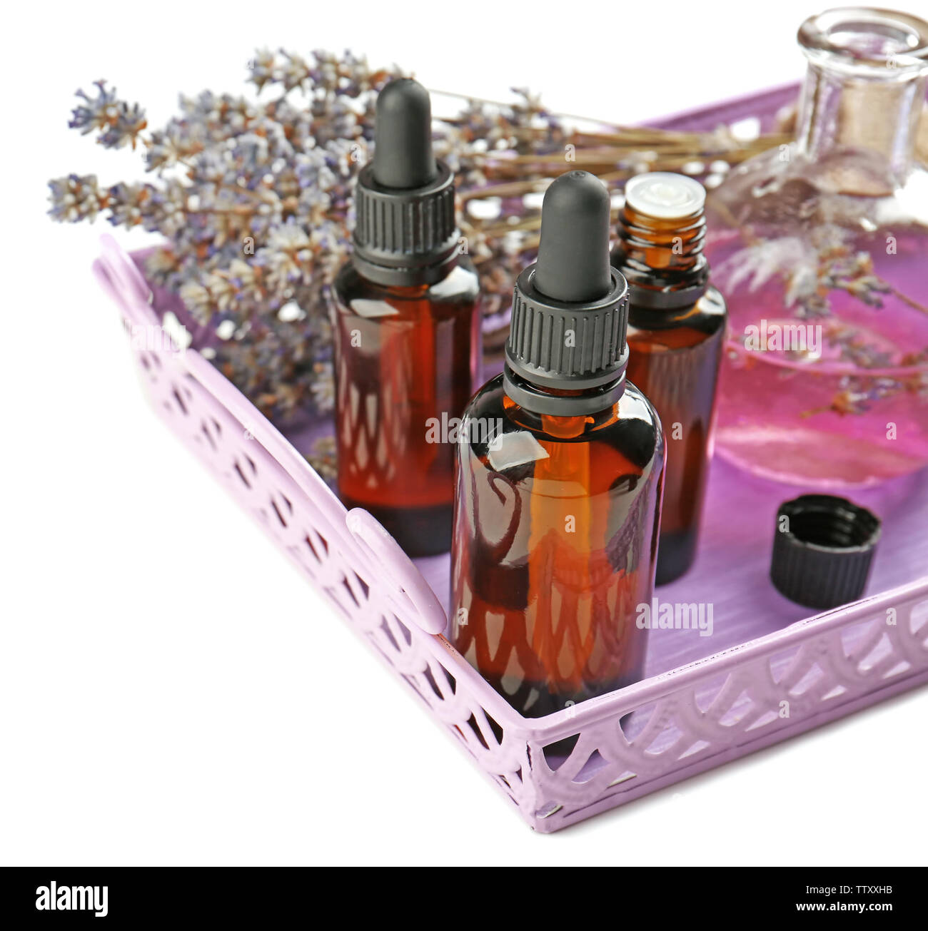Bottles with essential oil and lavender in tray on white background ...