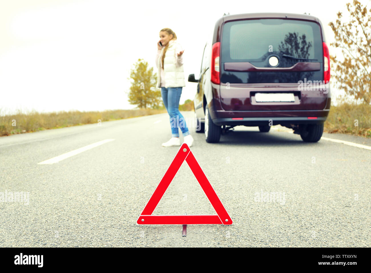 Traffic warning sign on road with car and female driver on background ...