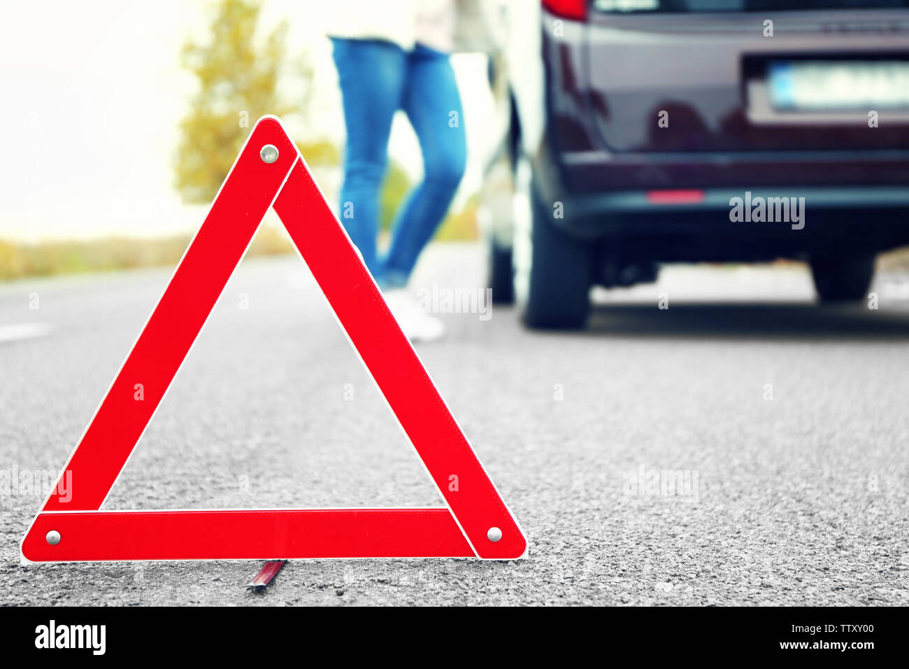 Traffic warning sign on road with car and female driver on background ...