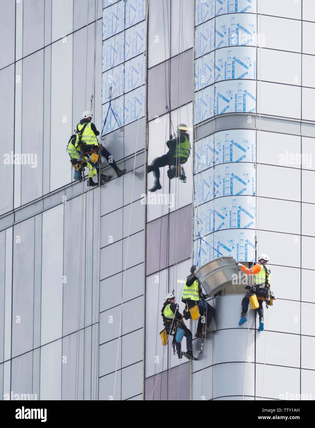 Workers use abseiling equipment to replace exterior unsafe cladding similar to that used in Grenfel Tower on the Queen Elizabeth Hospital in Glasgow. Stock Photo