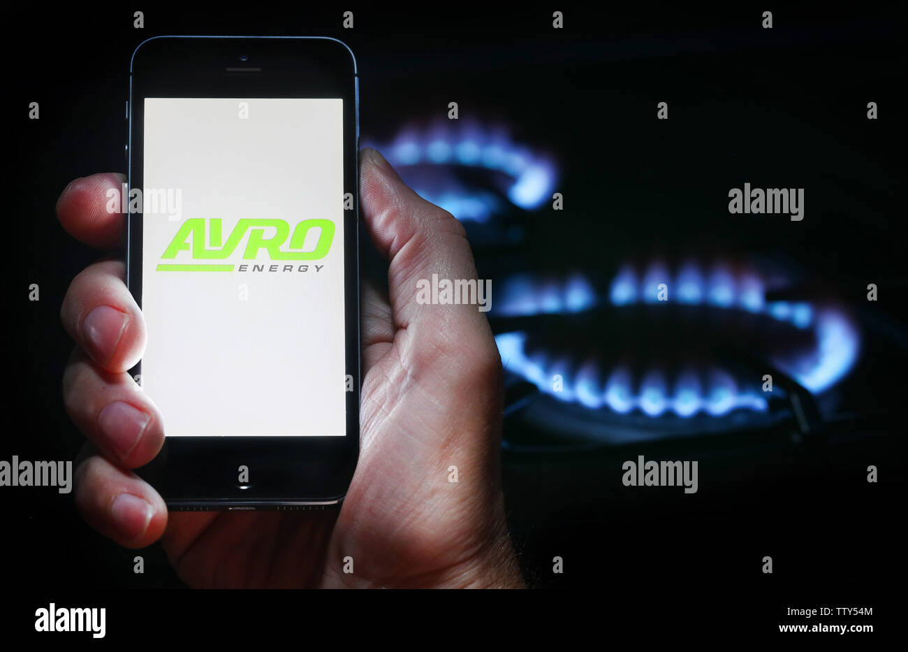 A man looking at the website logo for energy company Avro on his phone in front of his gas cooker (editorial use only) Stock Photo