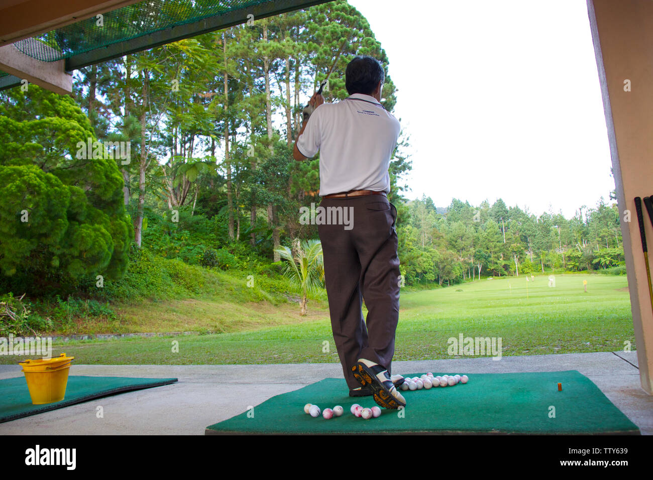 Man practicing golf at driving range Stock Photo
