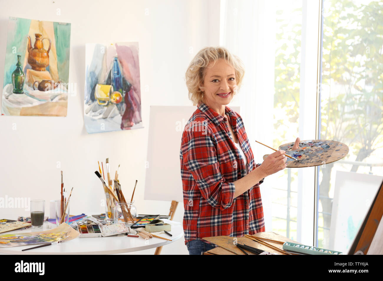 Senior female artist with palette and brush in studio Stock Photo - Alamy