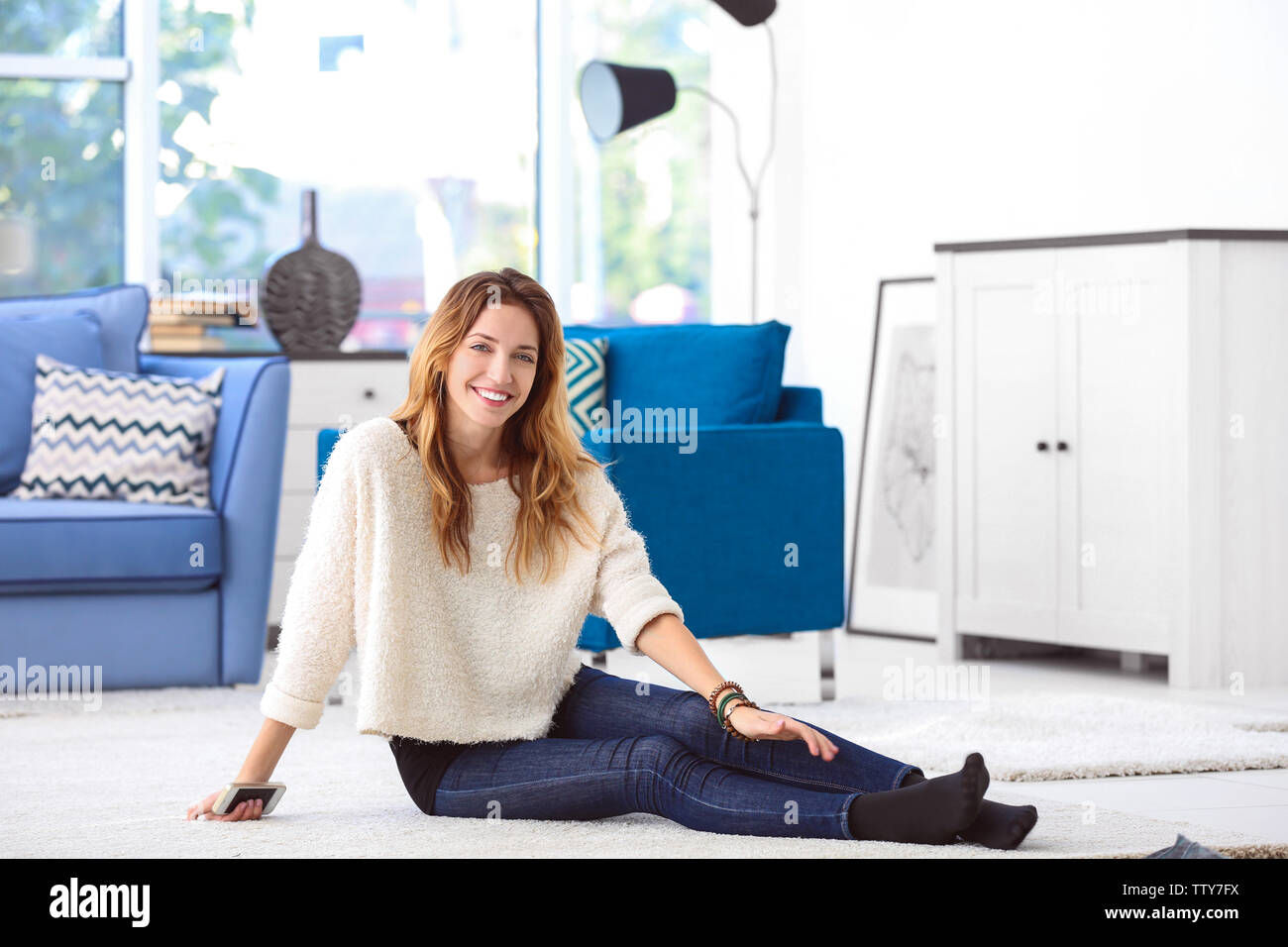 Portrait of young woman sitting on floor in room Stock Photo - Alamy
