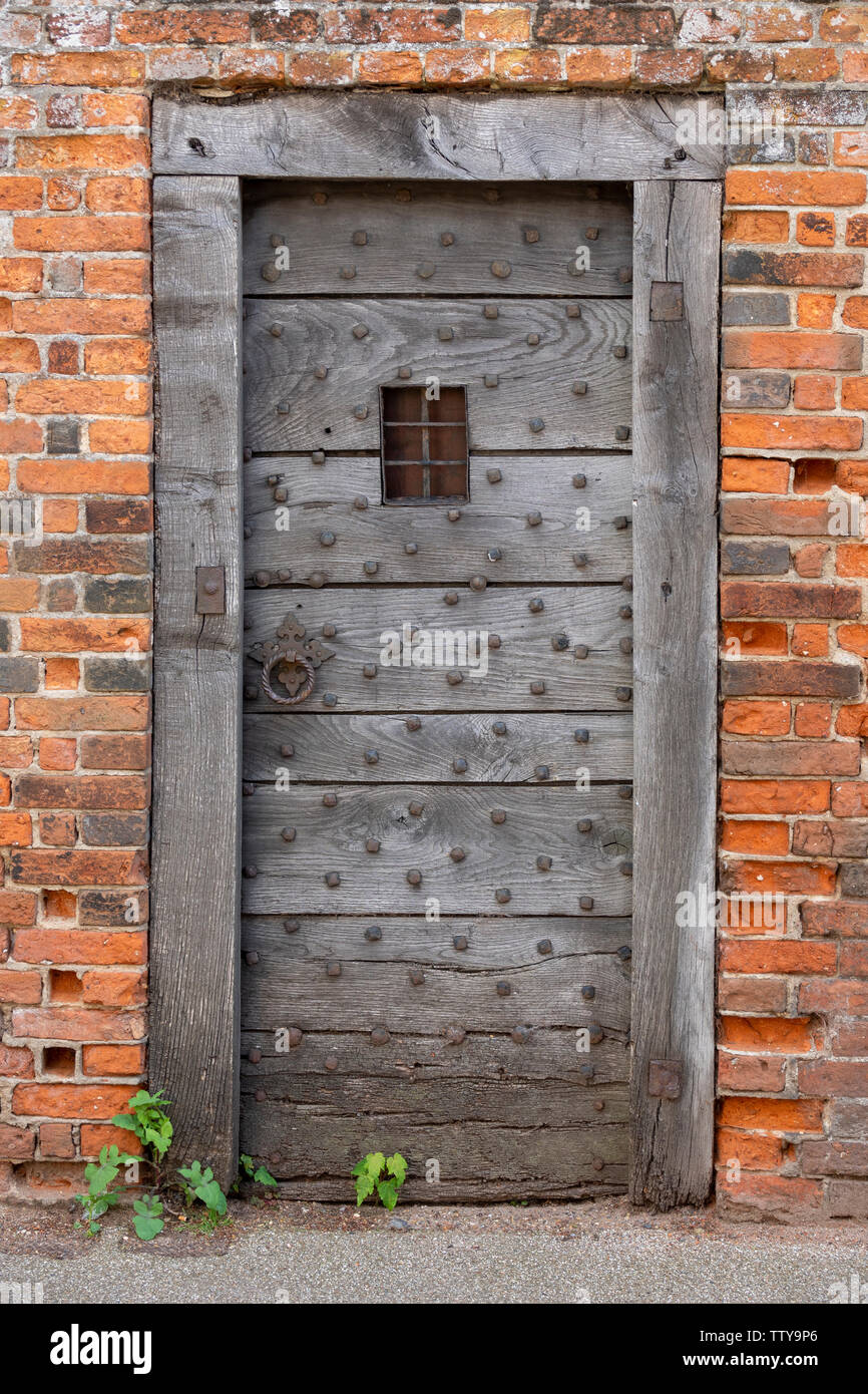 Antigue oak door with viewing grille, oak frame surround and period red bricks Stock Photo