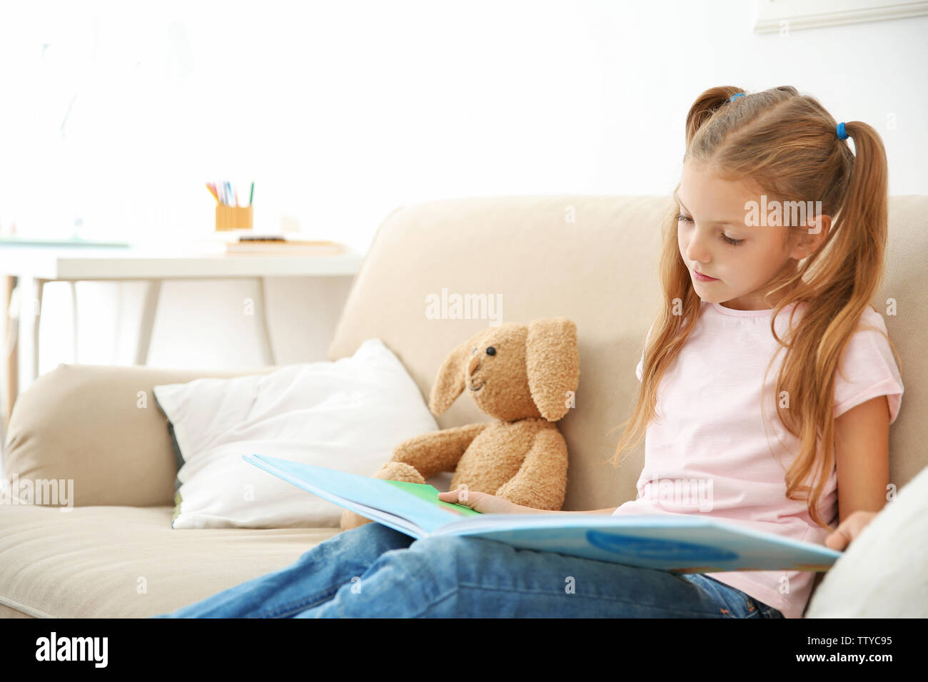 Cute girl with book at home Stock Photo - Alamy