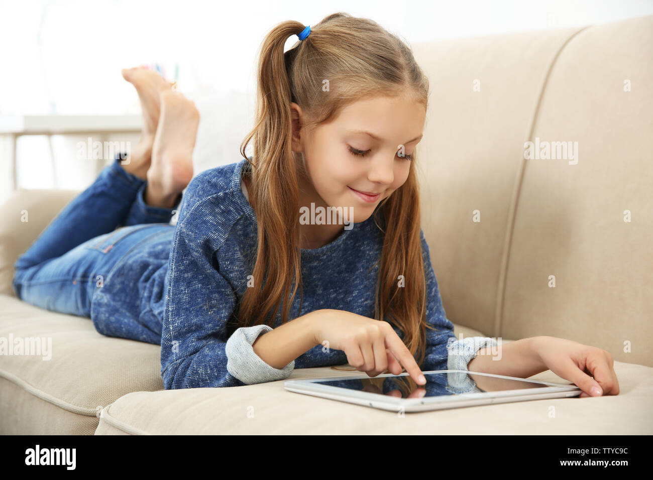 Cute girl lying on sofa with tablet computer Stock Photo - Alamy