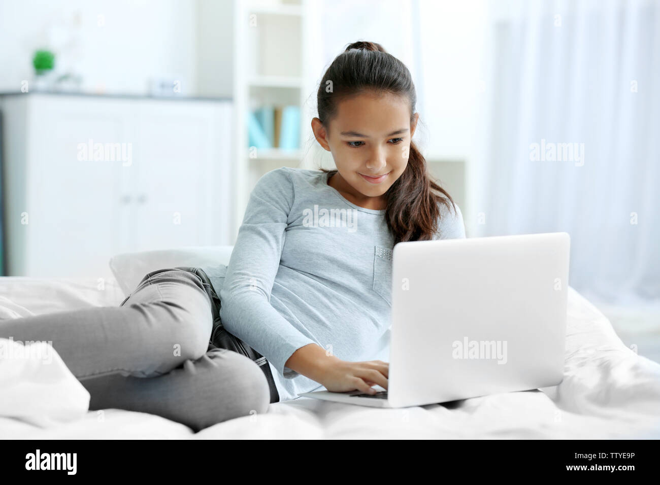 Cute girl lying on bed with laptop Stock Photo - Alamy
