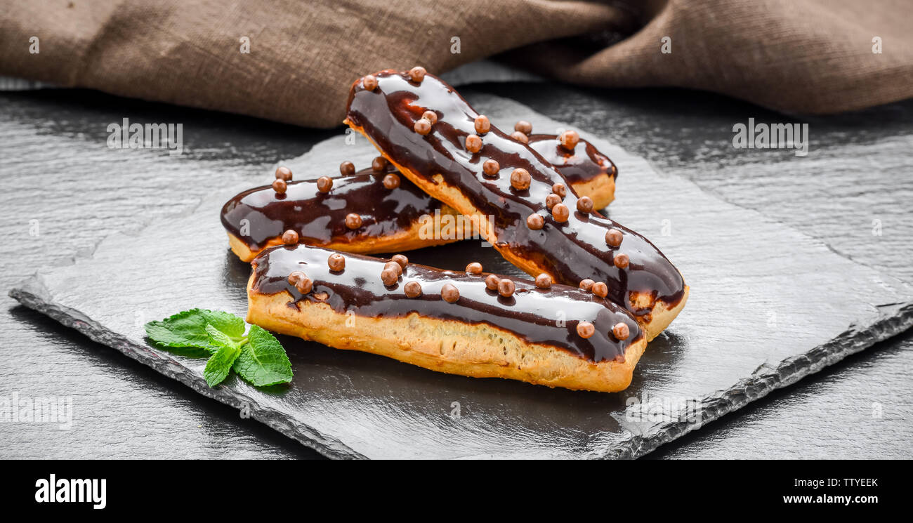 Traditional French dessert. Eclair with chocolate icing and raspberries. Dark background Stock Photo