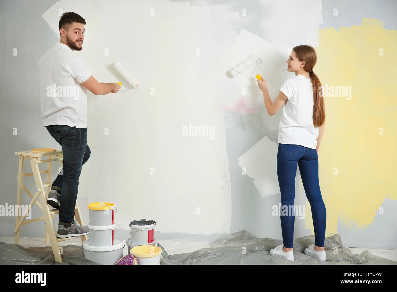 Young decorators painting wall in room Stock Photo