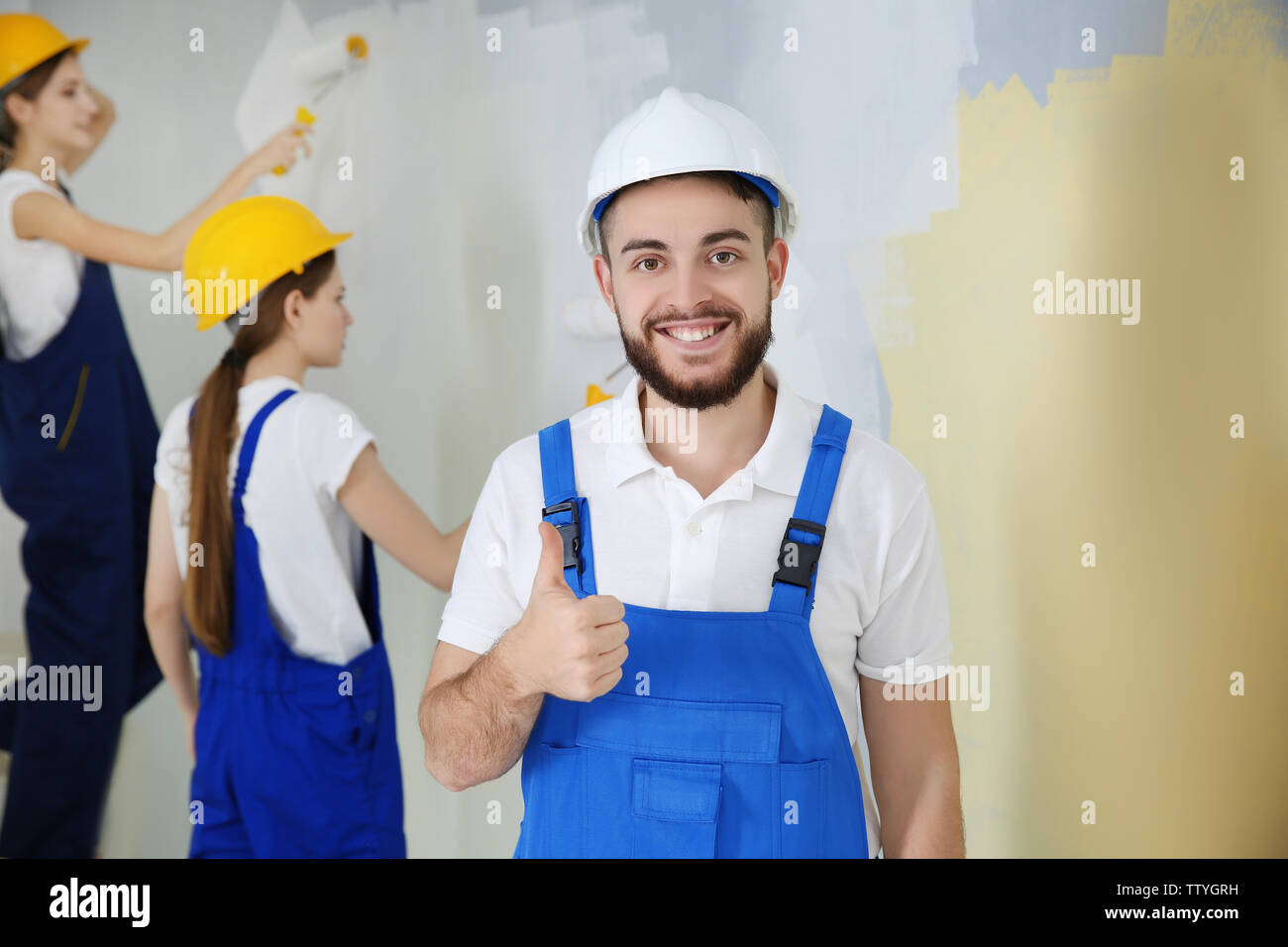 Young decorators painting wall in room Stock Photo