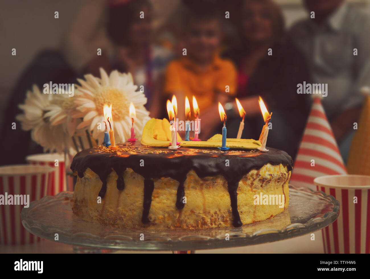 Birthday cake with alight candles and big family on background Stock ...