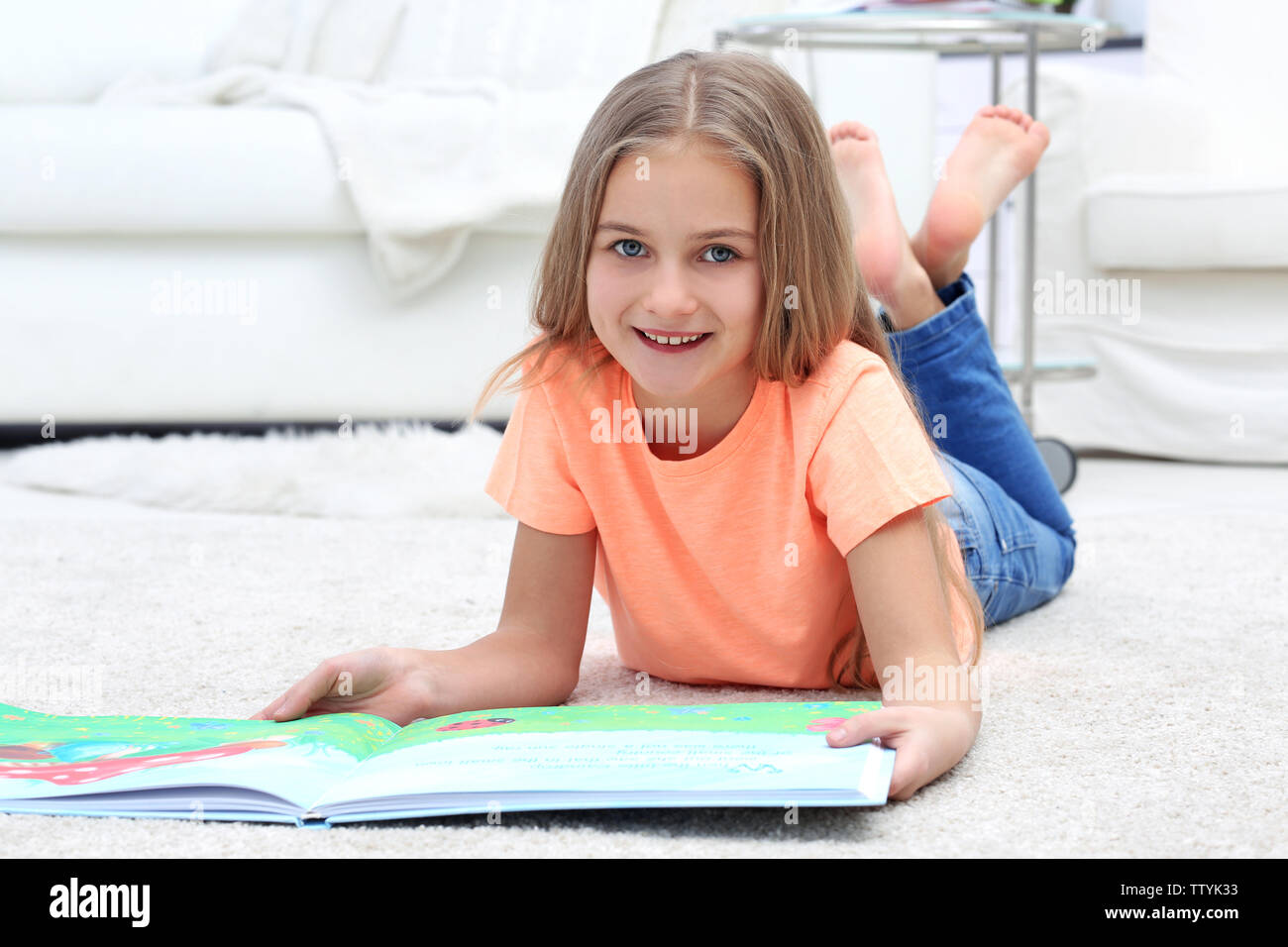Cute little girl with book lying on the floor at home Stock Photo - Alamy