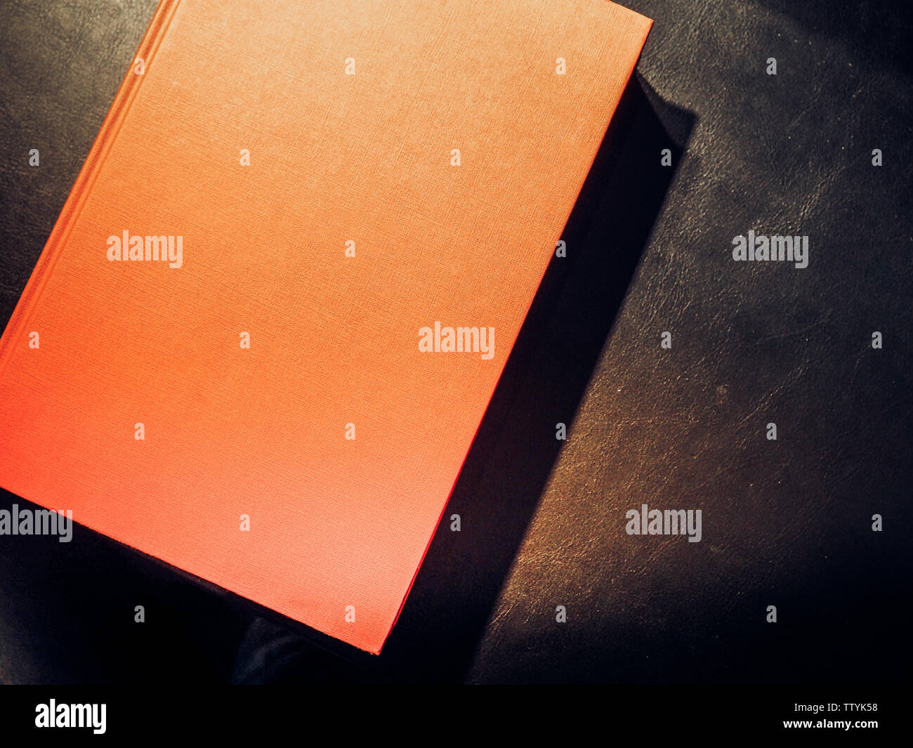 Red hardback book on black table, Office dark table. Mock up book blank black, red, white, leather cover for magazine, booklet, brochure, diary, busin Stock Photo