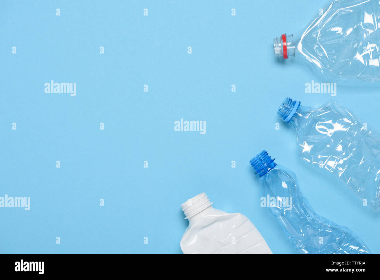 Single use crushed plastic water bottles on blue background with copy space. Plastic pollution. Recycle reuse template. Stock Photo