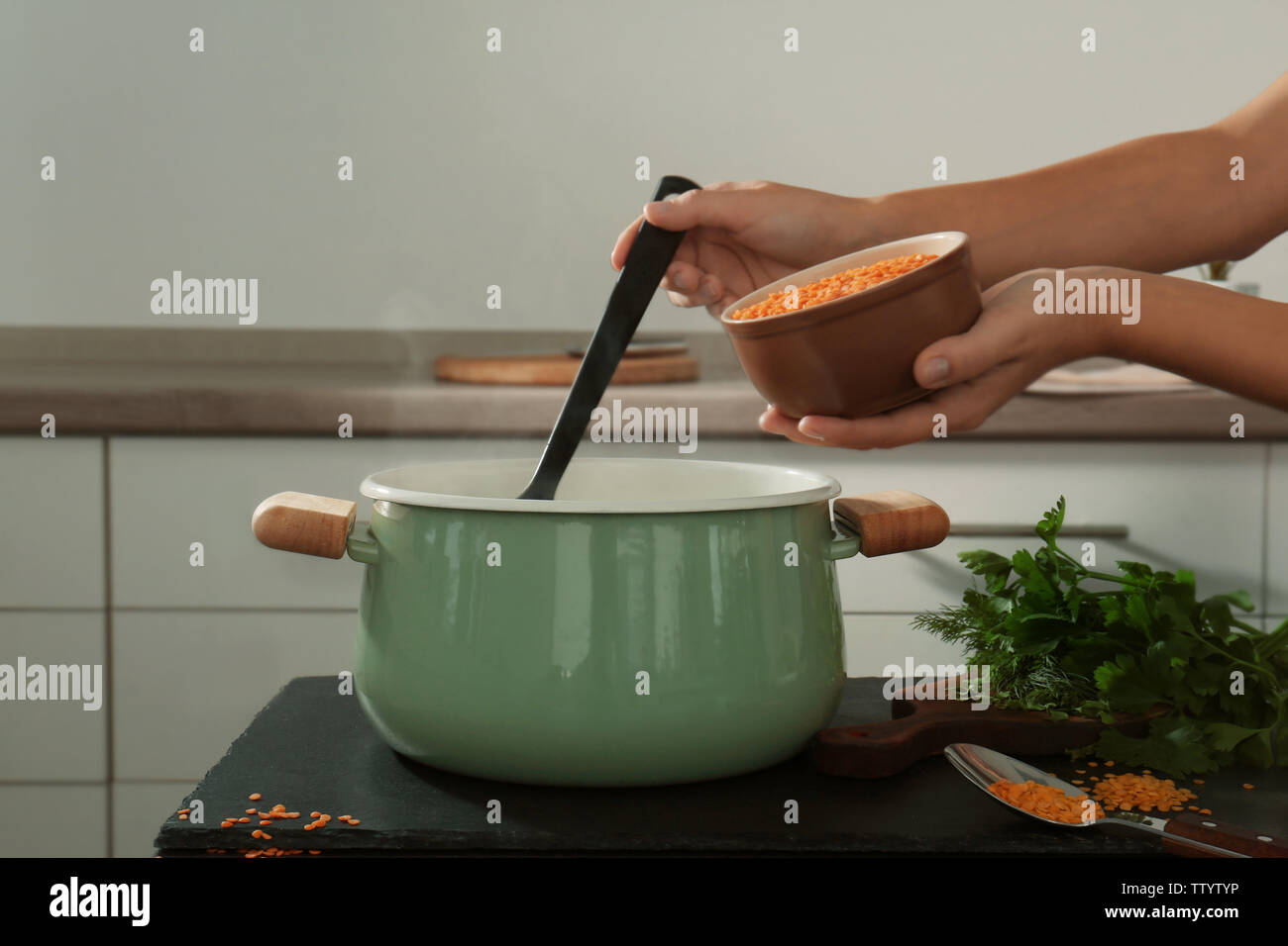 Female hand holding ladle and bowl lentil above enamelled pan in ...
