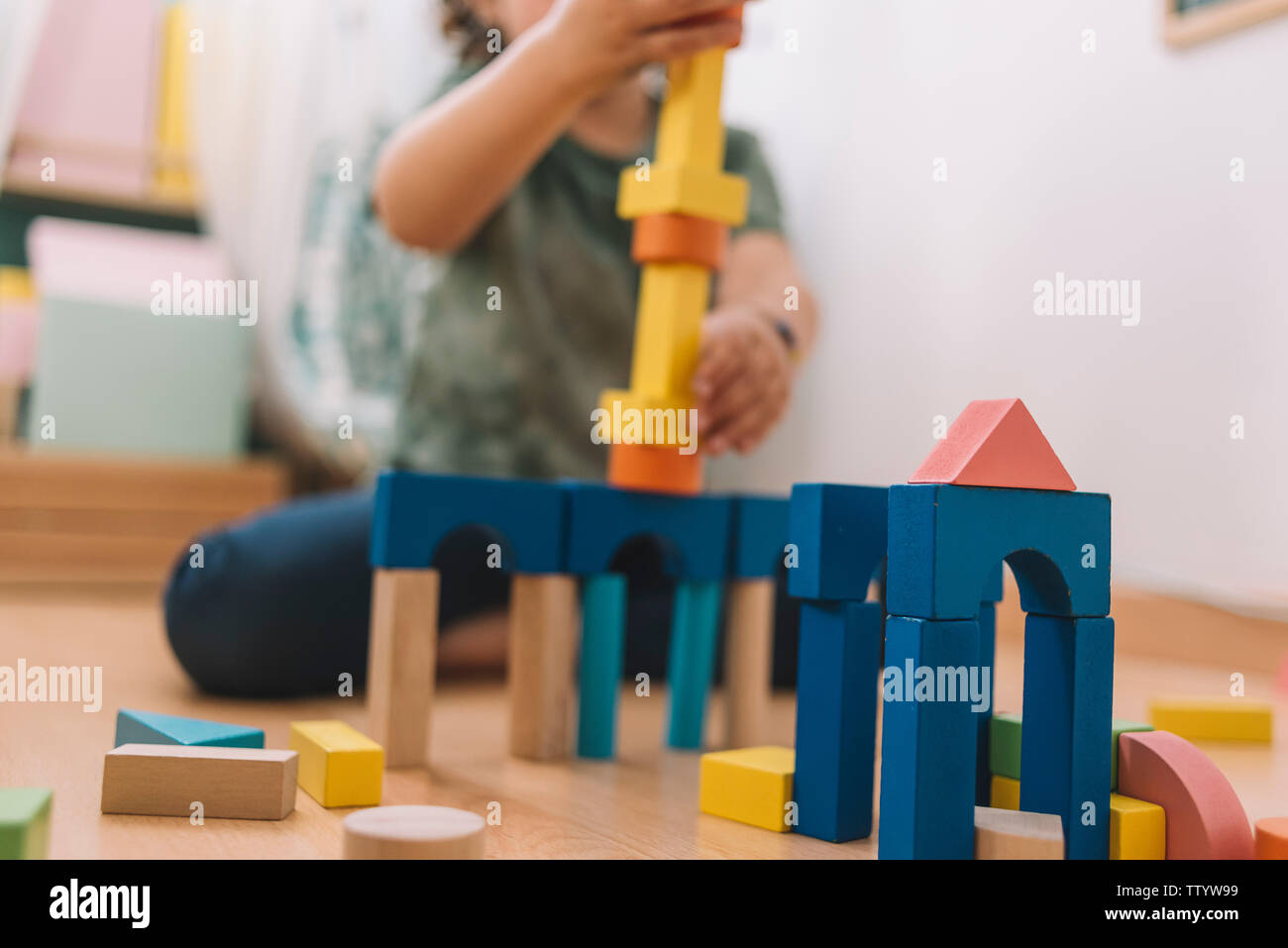 colorful wooden building blocks with a little girl unfocused in the ...