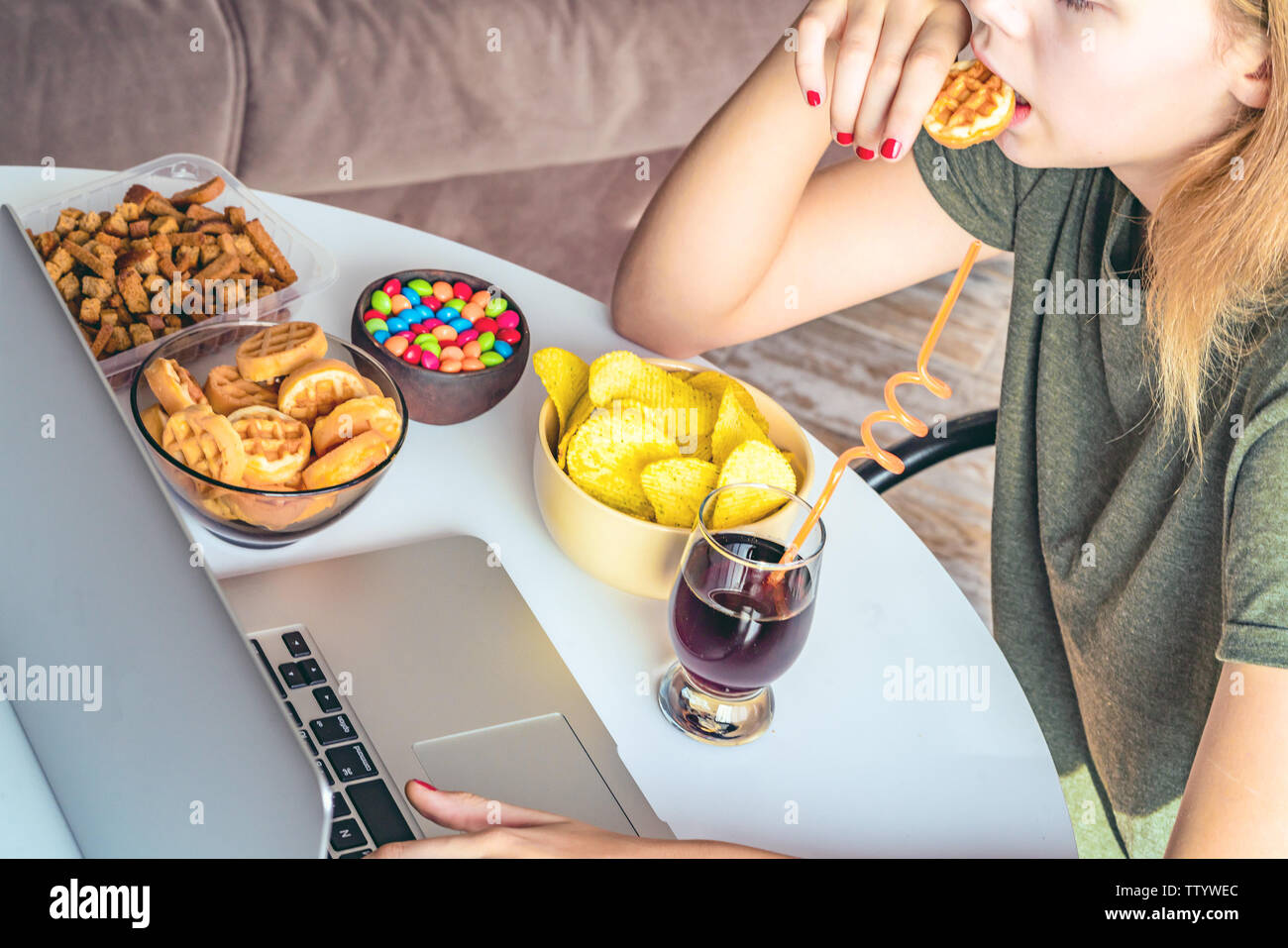 Girl works at a computer and eats fast food. Unhealthy food: chips ...