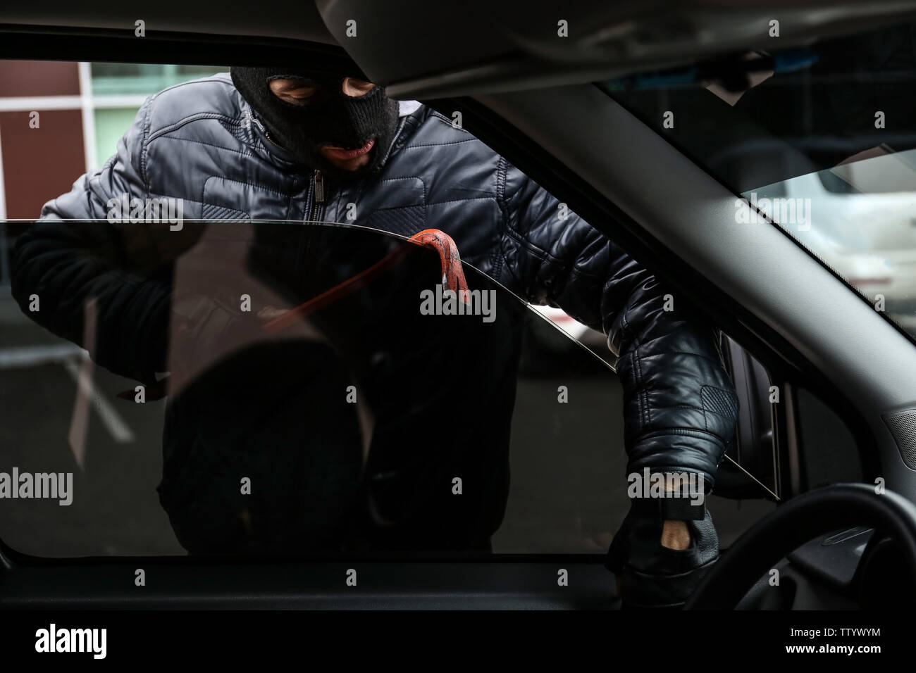 Male thief getting into car through window Stock Photo - Alamy
