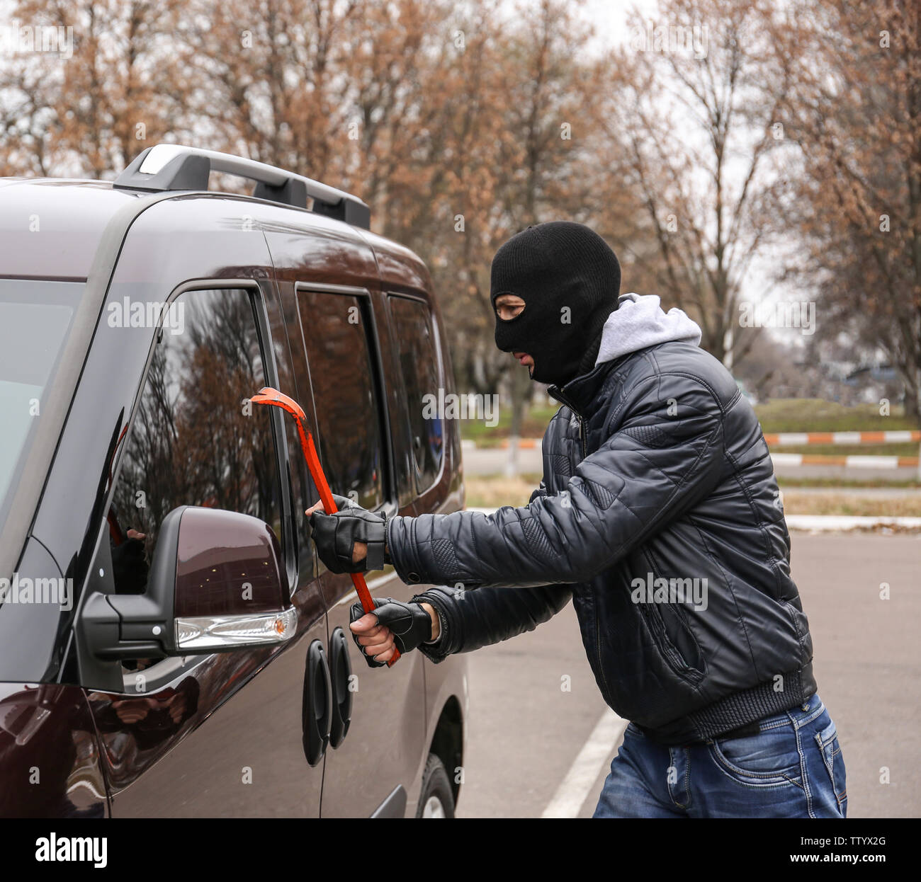Male thief going to break car window with crowbar Stock Photo - Alamy