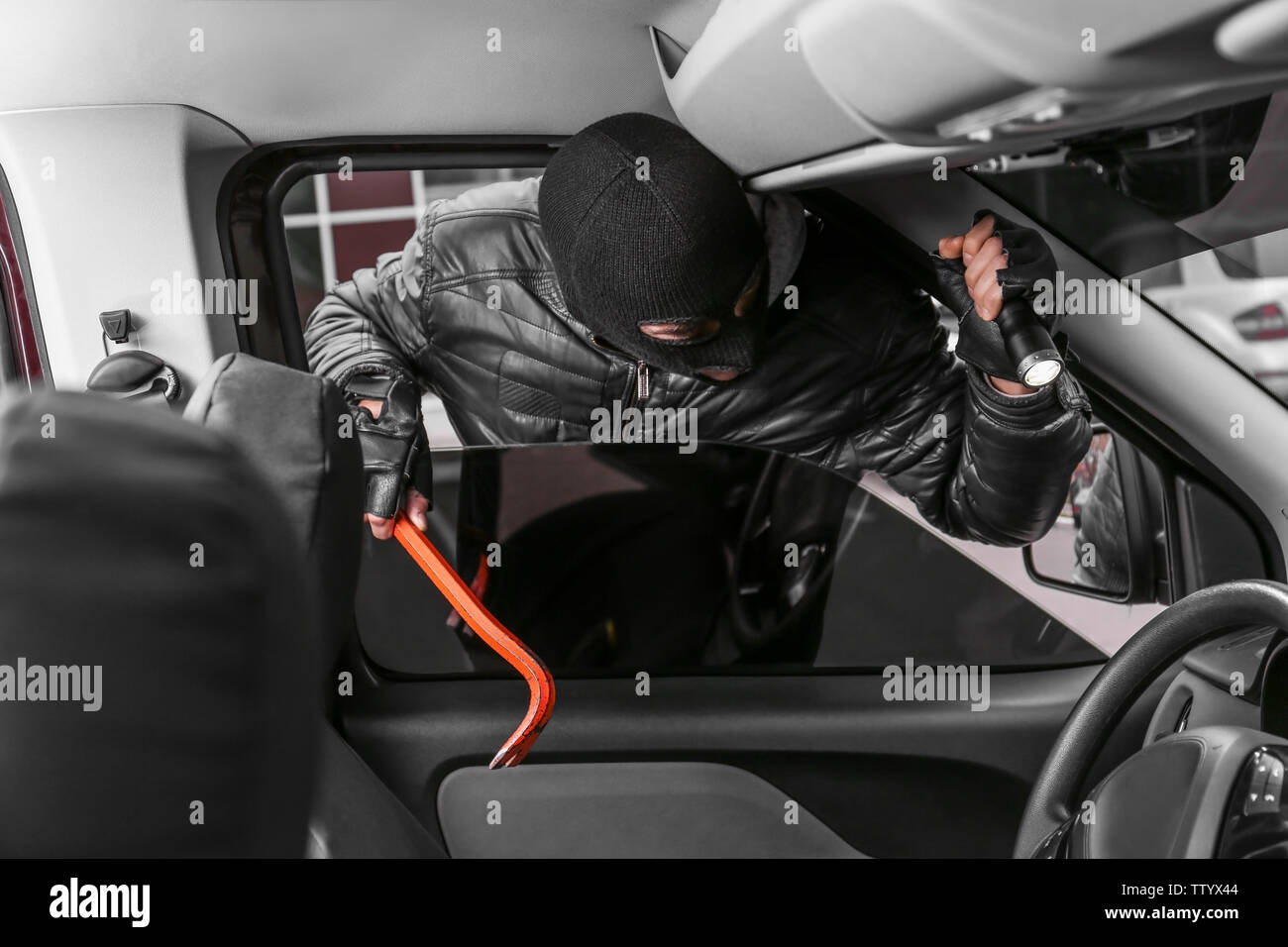 Male thief getting into car through window Stock Photo - Alamy