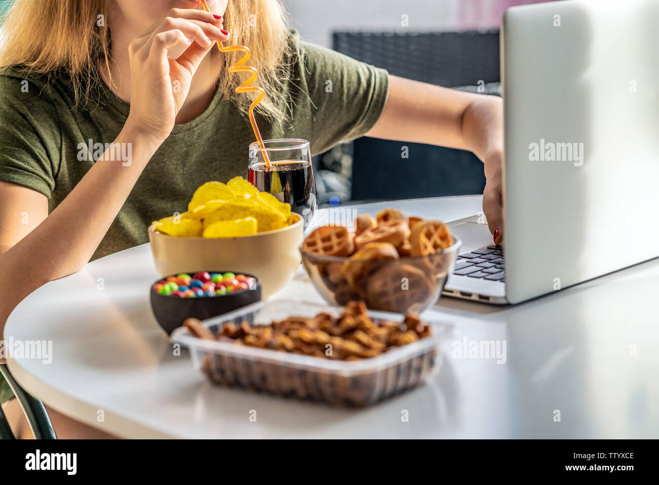 Girl works at a computer and eats fast food. Unhealthy food: chips ...