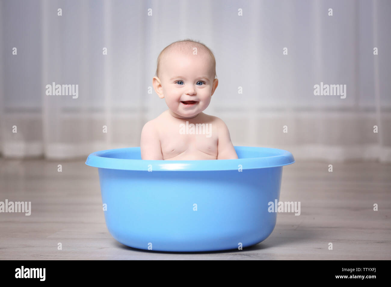 Cute baby in plastic basin at home Stock Photo Alamy