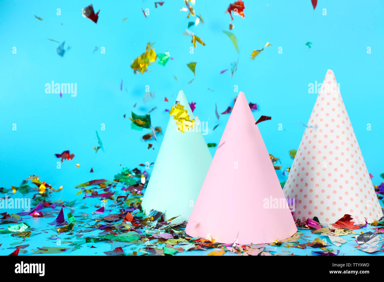 Party hats with colorful confetti on color background Stock Photo - Alamy