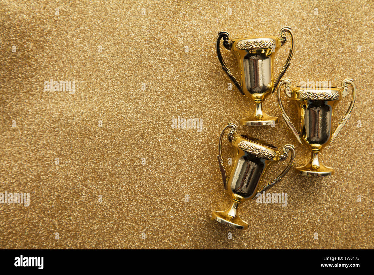 Gold winners achievement trophy on a gold glitter background Stock