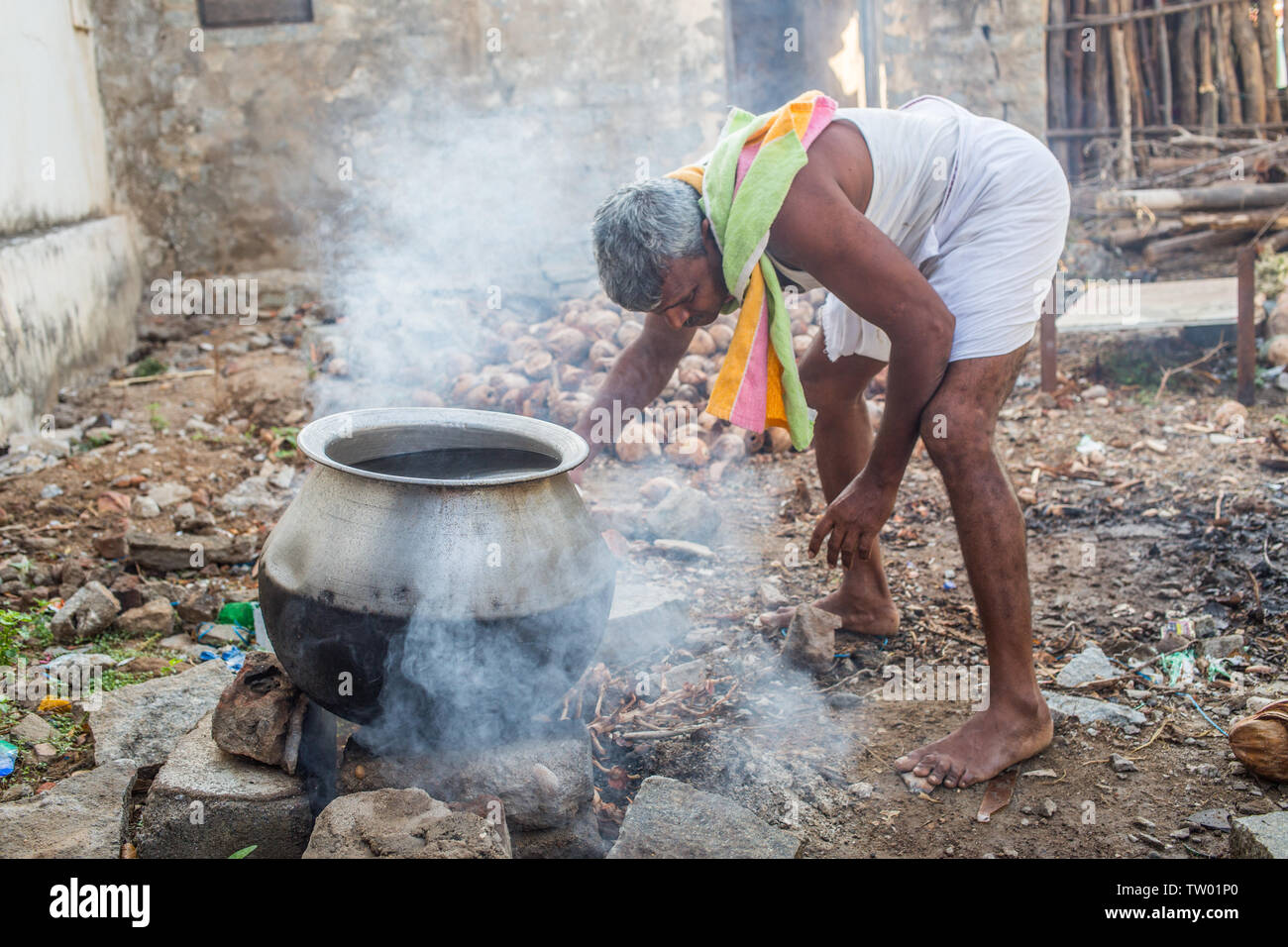 A man heating up water over an open fire for a morning bath in south
