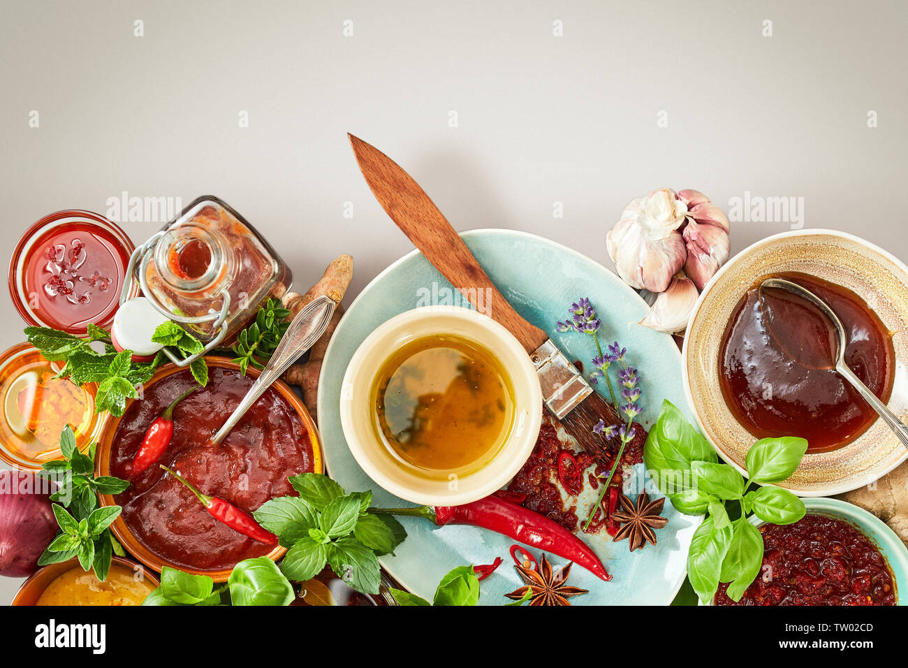 Fresh herbs, marinades and sauces for a summer BBQ arranged as a bottom