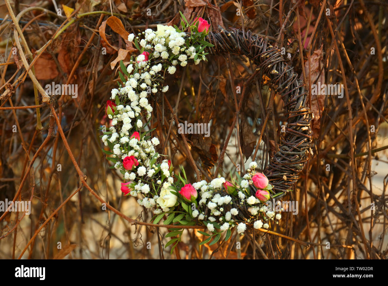 Floral wreath with beautiful flowers on grapevine background Stock Photo