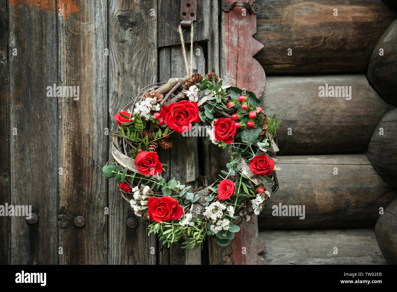 Floral wreath with beautiful flowers hanging on vintage wooden door ...